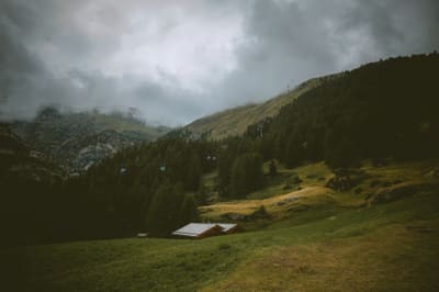 Wooden cabin in an alpine meadow under storm clouds